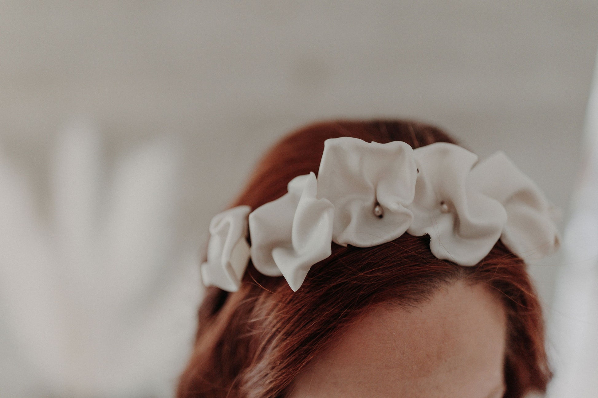 Couronne Celeste en fleurs blanches en porcelaine sur cheveux bouclés